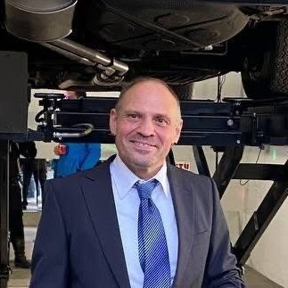 Dipl.-Ing. Ulf Witte in der Prüfstelle, unter einem angehobenen Fahrzeug